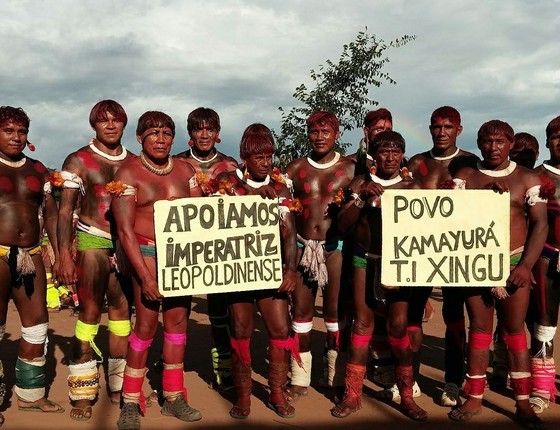 Índios da Terra Indígena do Xingu posam para foto com cartaz em apoio à escola de samba carioca Imperatriz Leopoldinense. A escola desfilará com um enredo sobre a defesa da floresta e enfrenta críticas de setores do agronegócio