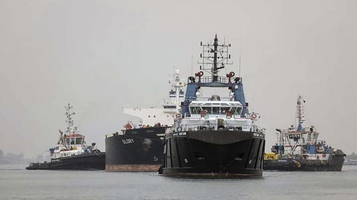 Tugboats pull a ship in the Suez Canal between the cities of Port Said and Ismailiya, Egypt