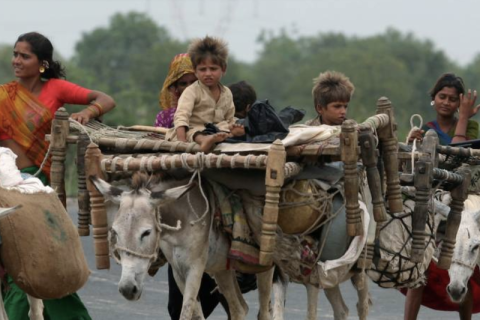 Tribal people walk with their belongings in Tarapur village, about 87 km (54 miles) south from the western Indian city of Ahmedabad July 13, 2007. REUTERS/Amit Dave (INDIA)